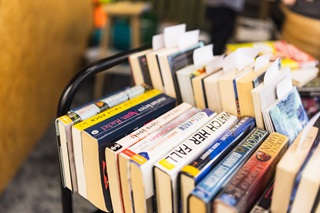 Close up of a trolley stacked with books.