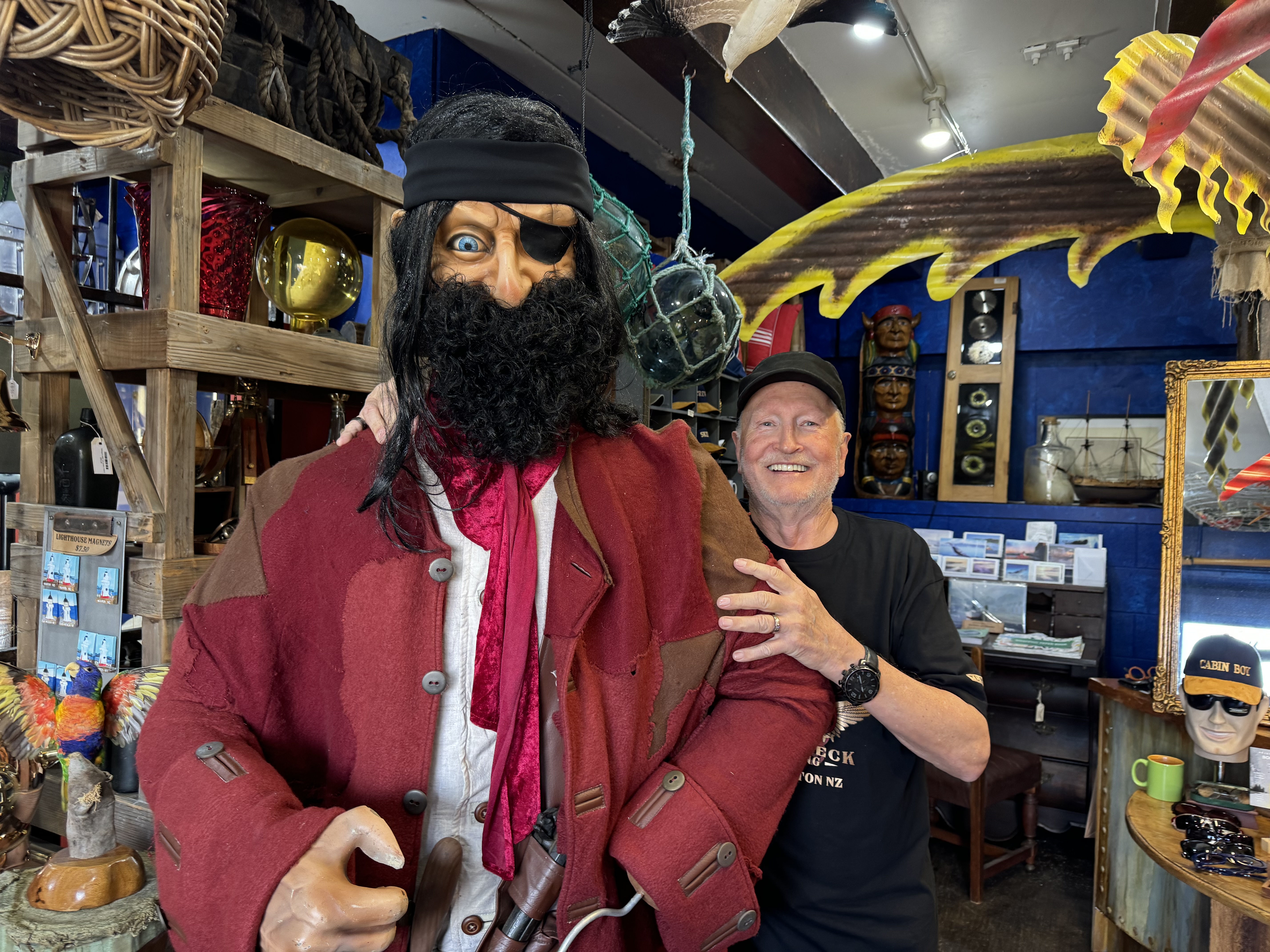 Man smiling next to a large puppet pirate.