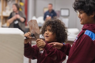 Young kids having a go at sculpting a wooden block.