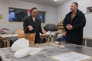Two people creating artwork over a table full of stone.