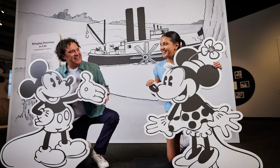 A father and daughter pose with cardboard cut-outs of Mickey and Minnie Mouse on display at the Disney: Magic of Animation exhibition.