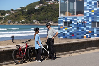 Two people standing infront of the beach next to bikes.