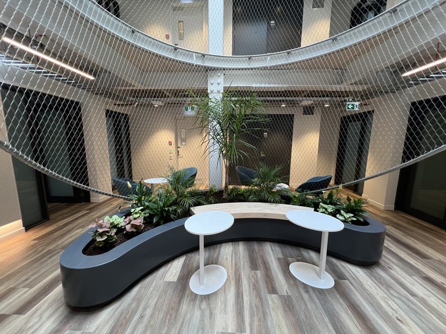 Seats inside a building with planter boxes and netting surrounding the seats.