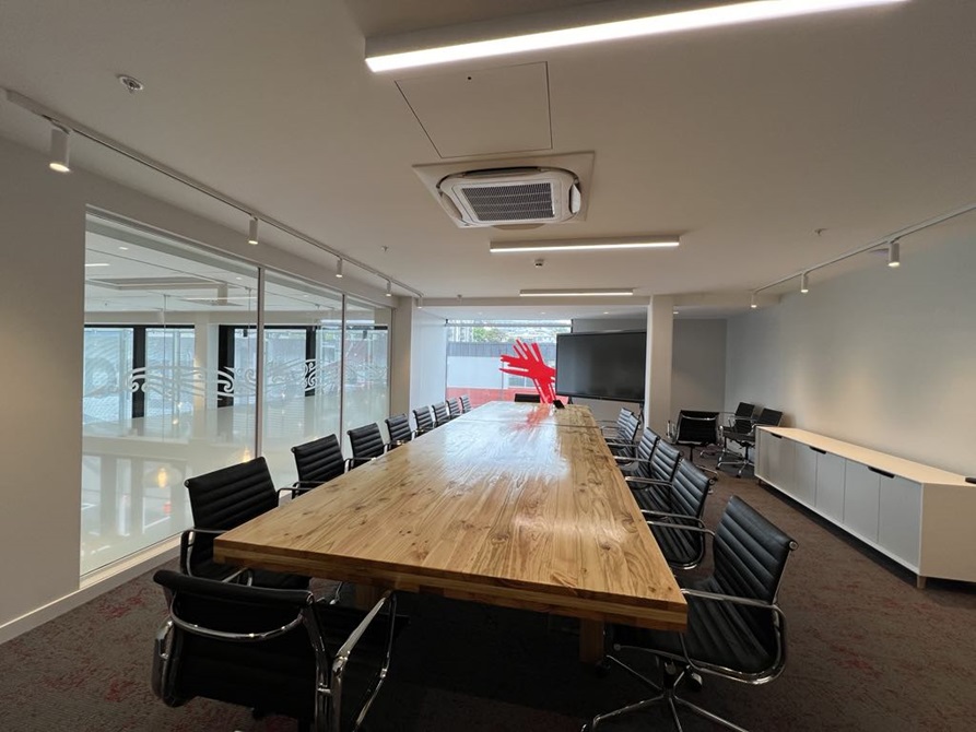 Board room with black leather chairs surrounding a wooden table.