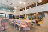 Cafe with multicoloured chairs and lights hanging down.