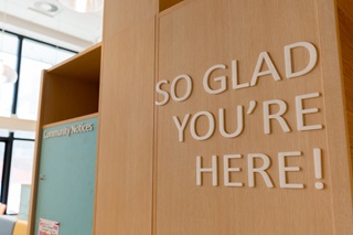 A wooden cabinet with 'So glad you're here' written on it.