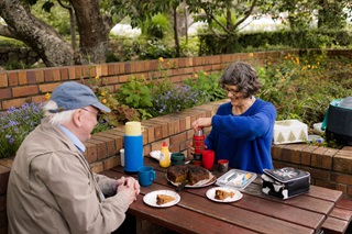 People sitting and having food at a picnic table.