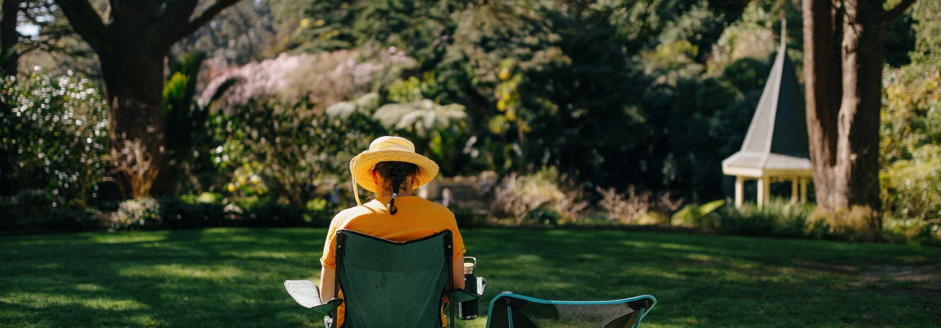 A person sitting on a camping chair in the grass.