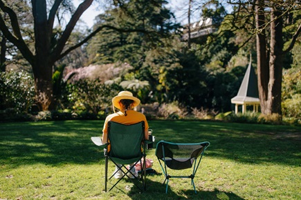 A person sitting on a camping chair in the grass.