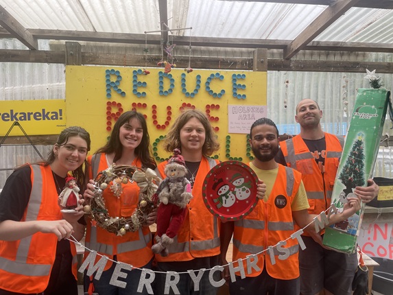 Group of staff members from the tip shop smiling and holding out second hand items.