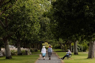 Two people walking a dog in a park.