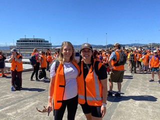 Two women in high vis vests standing next to each other. 