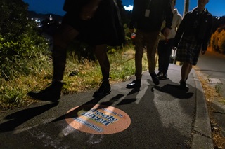 Close up of people's feet as they walk down a road with a decal on the pathway.