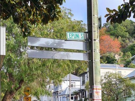 Epuni Street sign on pole with new street name sign covered ahead of unveiling.