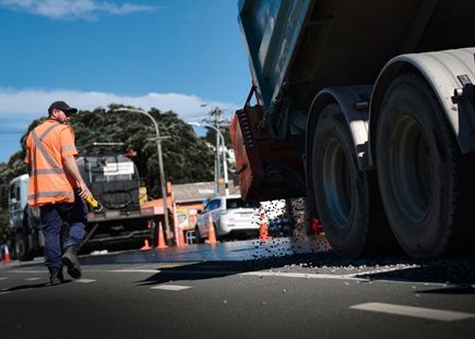 image of chipseal being poured onto the road from a truck.