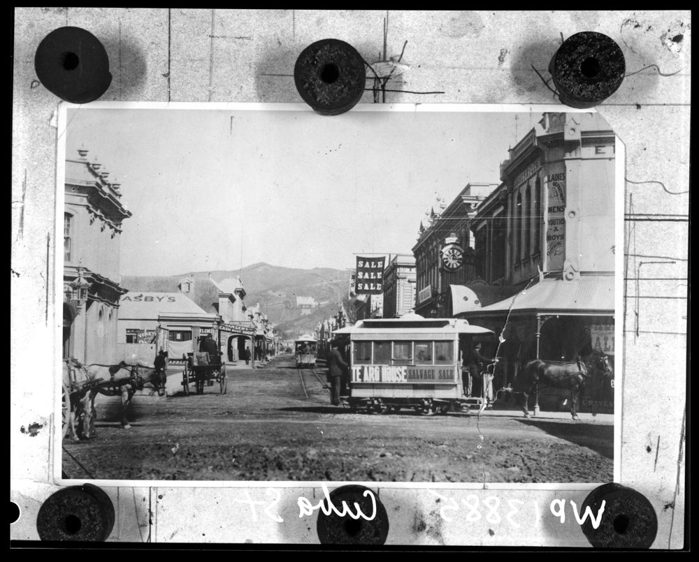 Image of Horse Trams in Cuba Street, corner of Dixon Street. Te Aro House in the background is advertising a Salvage Sale.