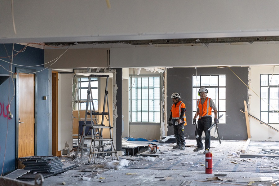 Two workers in high vis in the middle of a floor undergoing construction.