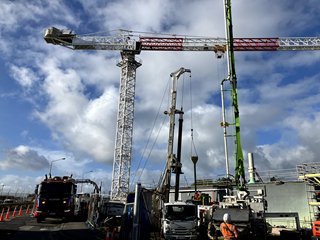 Crane towering above work trucks and vans during construction.
