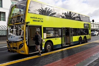 Double decker Metlink bus pulled over to the side of the road near a bus platform.
