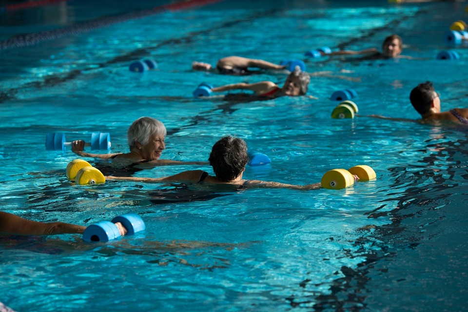 Women chatting in swimming pool while doing exercises during Seniors' Week.