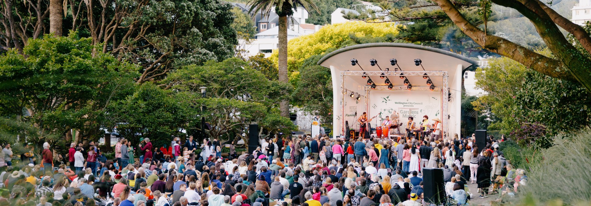 Crowd of people gathered infront of a stage watching Gardens Magic.