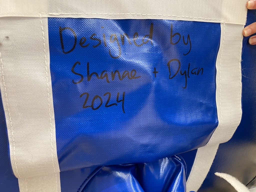 Flap of an inflatable that reads 'Designed by Shanae and Dylan 2024'