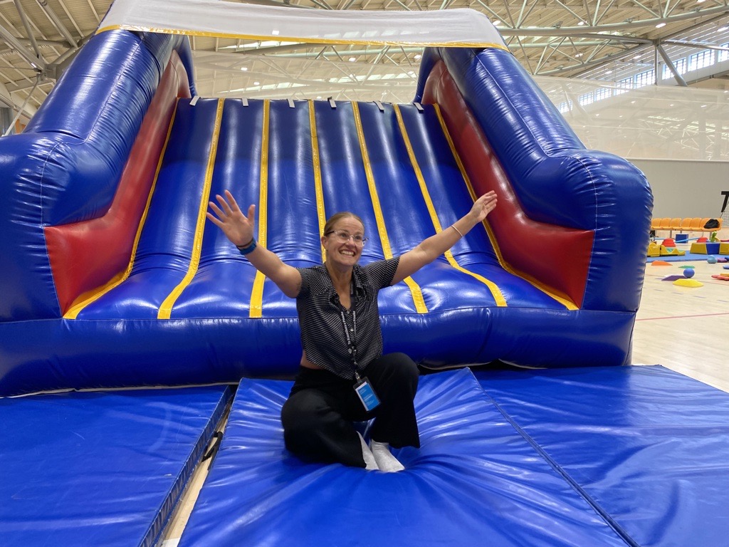 Woman posing with her arms up at the bottom of an inflatable slide.