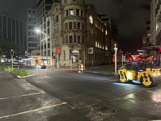 Road being sealed at nighttime with machinery operating.