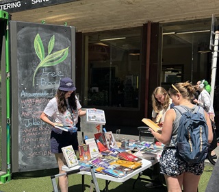 Librarian standing infront of a container with books on a table.