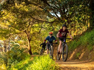 Two people riding their bikes on a track in the bush.