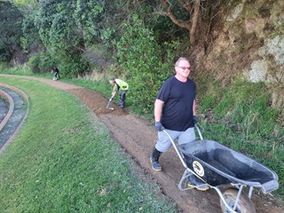 Person with a wheelbarrow and another person working on a track.