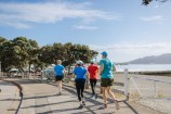 Group of people running on a concrete footpath.