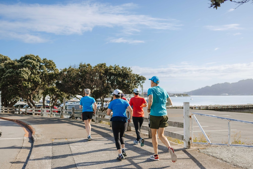 Group of people running on a concrete footpath.