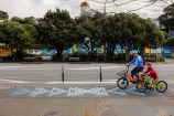 An adult and a child cycling in a bike lane with awa markings on the ground.