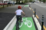 Child on a bike going down a bike lane with green markings.