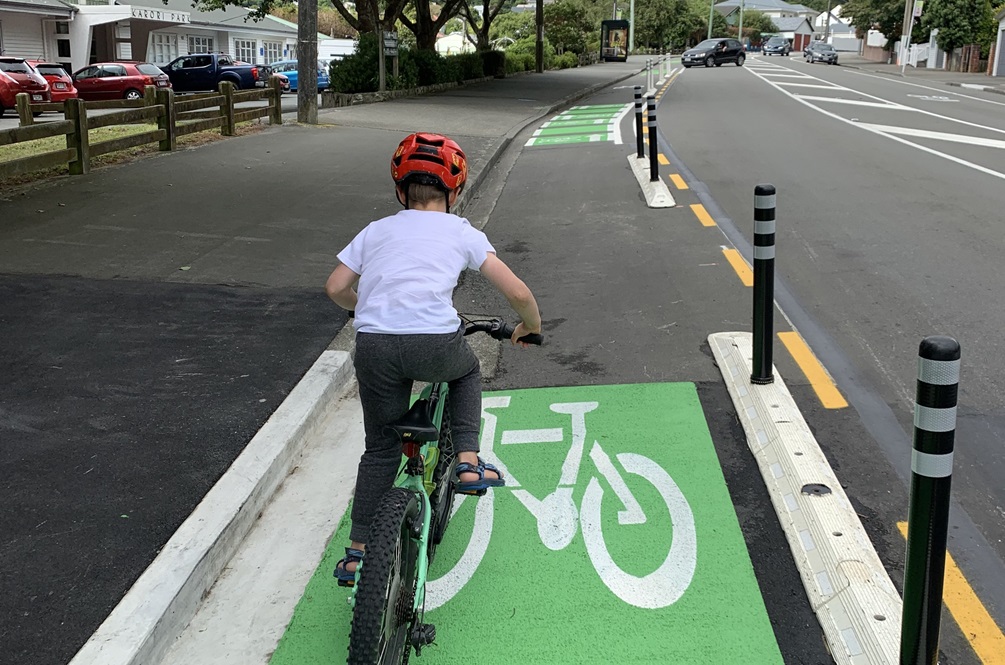 Child on a bike going down a bike lane with green markings.