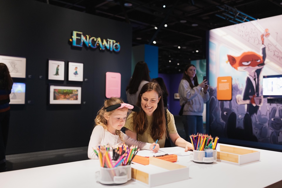 Child sketches at Disney exhibition with adult watches on