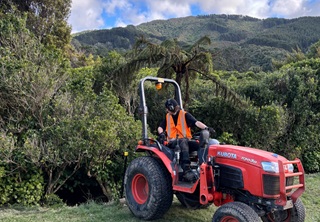 A red tractor with a man sitting in it wearing high vis. 