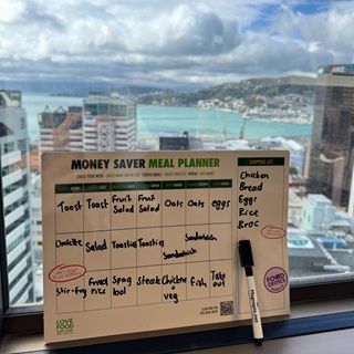 Meal planner leaning against a windowsill with the city in the background.