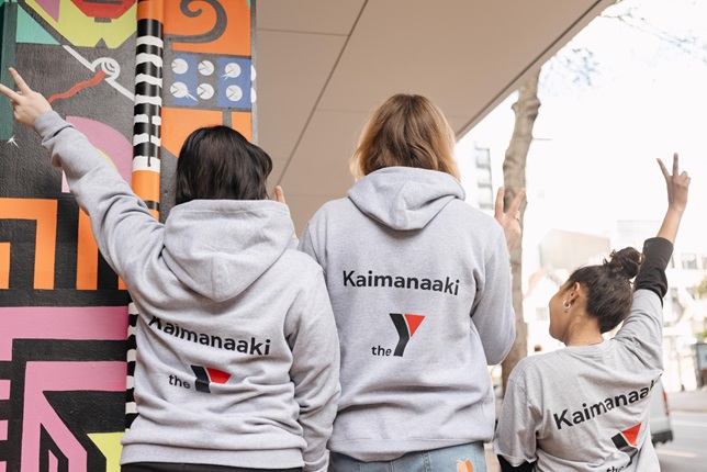 Three people in grey jerseys posing with Te Tai Ohinga branding on their tops.