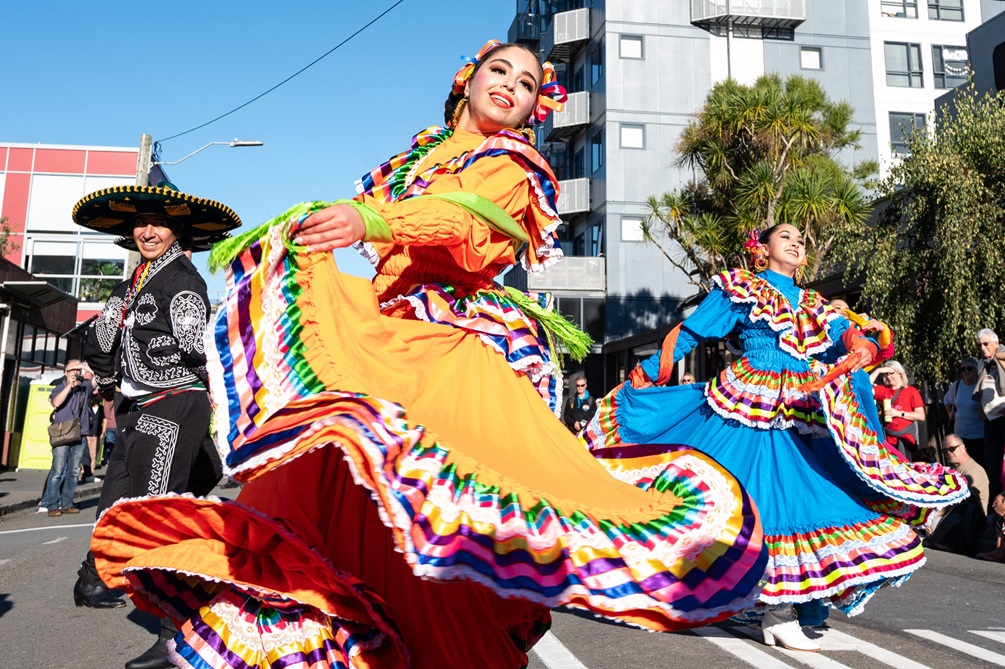 A person in a colourful dress dancing down the street.