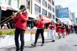A row of performers holding instruments and walking down the street.