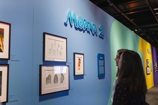 Two people looking at sketches on the wall.