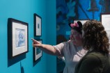 Two people looking at sketches on a wall, and pointing at them.