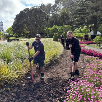 Two gardeners in the middle of tending to a garden.