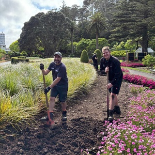 Two gardeners in the middle of tending to a garden.