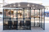 Bus shelter in the middle of an urban street with archival images on it.