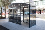 Bus shelter in the middle of an urban street with archival images on it.