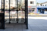 Bus shelter in the middle of an urban street with archival images on it.