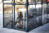 Bus shelter in the middle of an urban street with archival images on it.